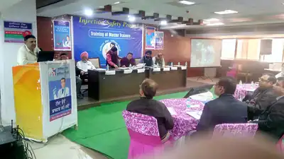Speaker addressing Injection Safety training of master trainers with stage banner (Punjab, 2019)
