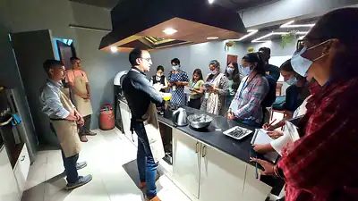 Participants watching cooking demonstration in demo kitchen, nutrition workshop
