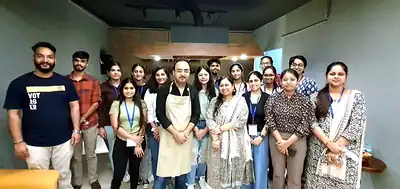 Participants and trainers in apron posing in training kitchen