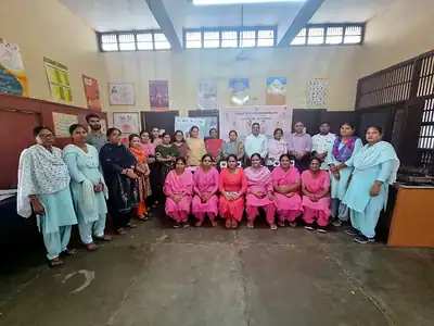 Anganwadi workers in pink and trainers posing in community room