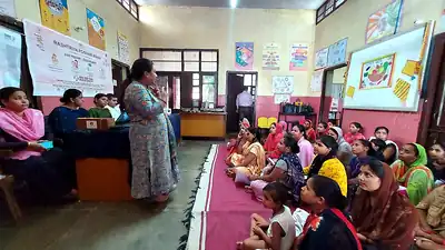 Speaker addressing women seated on floor at Rashtriya Poshan Maah session