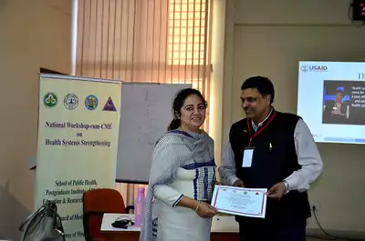 Woman faculty receiving certificate in front of banner at 2nd NWHSS 2016, PGIMER Chandigarh