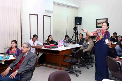 Woman faculty facilitating session with participants at tables at 2nd NWHSS 2016, PGIMER Chandigarh