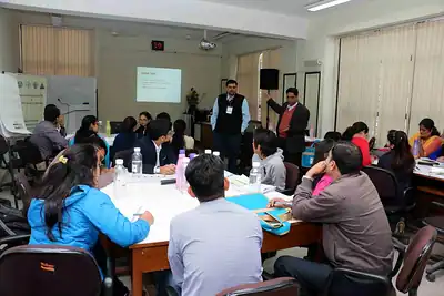 Group work session with participants at round tables and facilitators standing