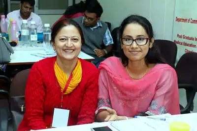 Two smiling women participants seated at workshop table at 2nd NWHSS 2016, PGIMER Chandigarh