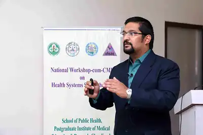 Speaker presenting with clicker at podium near banner at 2nd NWHSS 2016, PGIMER Chandigarh
